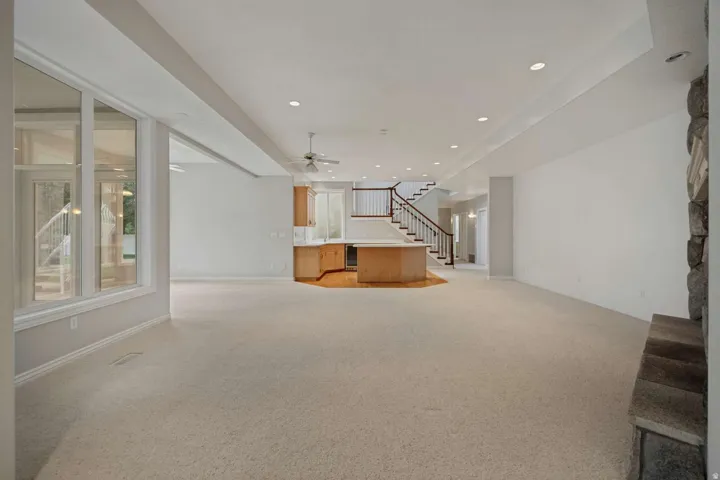 Expansive open concept lower level featuring light-toned carpet, recessed lighting, and a built-in wet bar with wood cabinetry