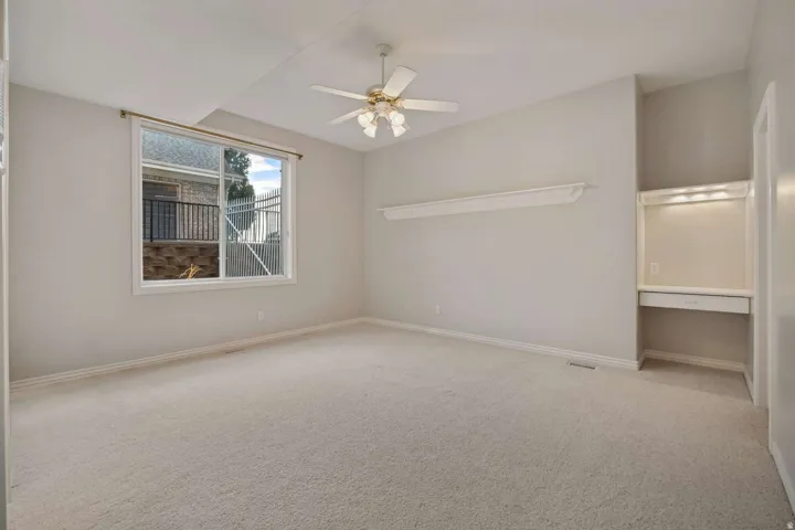 Carpeted flooring, ceiling fan, and built-in desk with integrated lighting