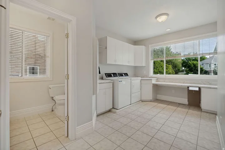 Spacious utility area featuring ceramic tile flooring, white cabinetry, a built-in countertop, and a large window