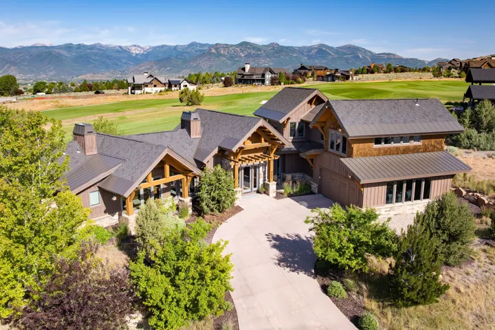 Contemporary mountain-style residence featuring a dark shingle roof, wood siding, and stone accents