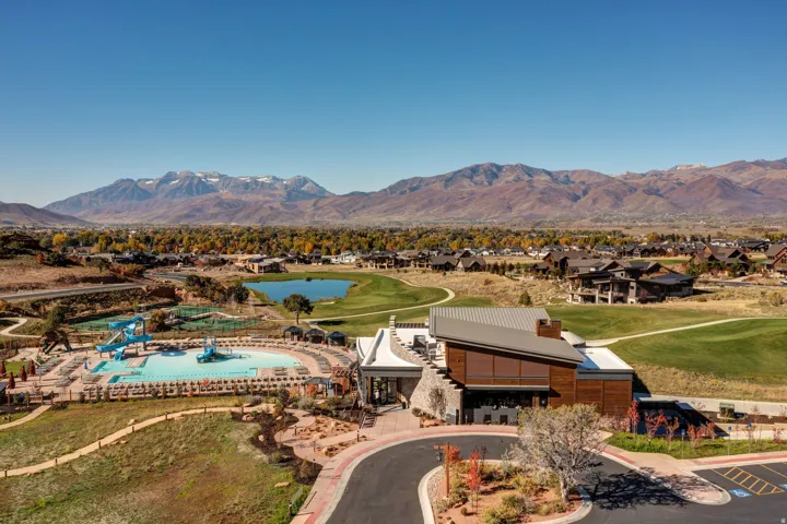 Expansive community amenities including a large swimming pool with water slides, a recreational building, and a manicured golf course with a central pond