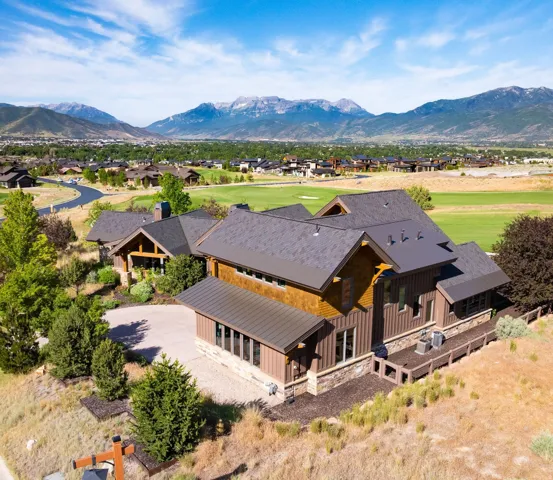 Mountain-backdrop residence featuring a multi-level roofline, wood siding, and stone accents