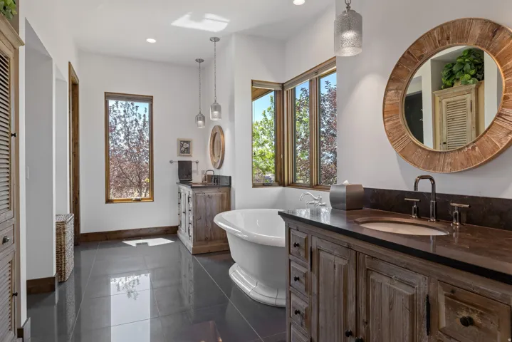 Freestanding soaking tub with dark tile flooring