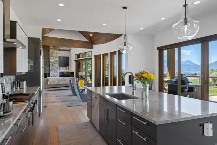 Open-concept kitchen featuring a large island with an undermount sink, pendant lighting, and contemporary cabinetry