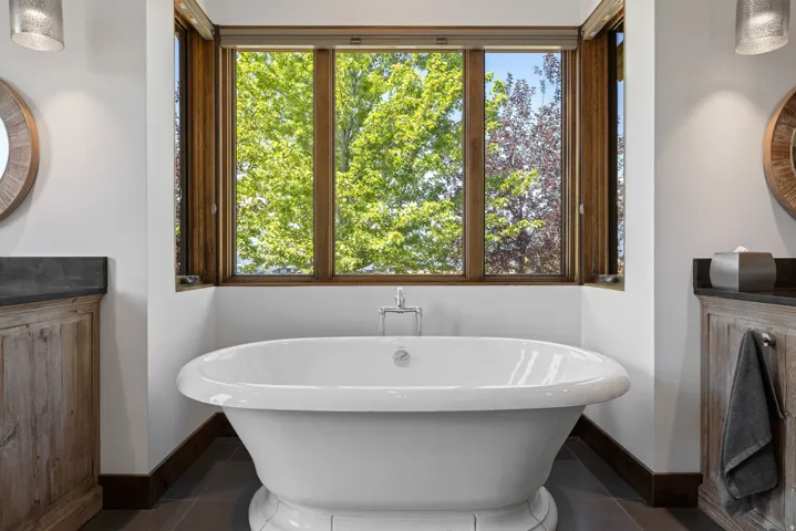 Freestanding soaking tub centered under a multi-pane wood-framed window