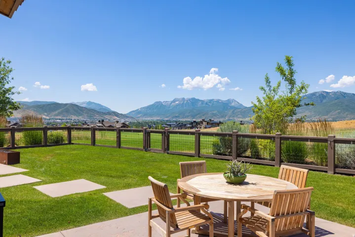 Patio area featuring concrete pavers, a manicured lawn, and a perimeter fence