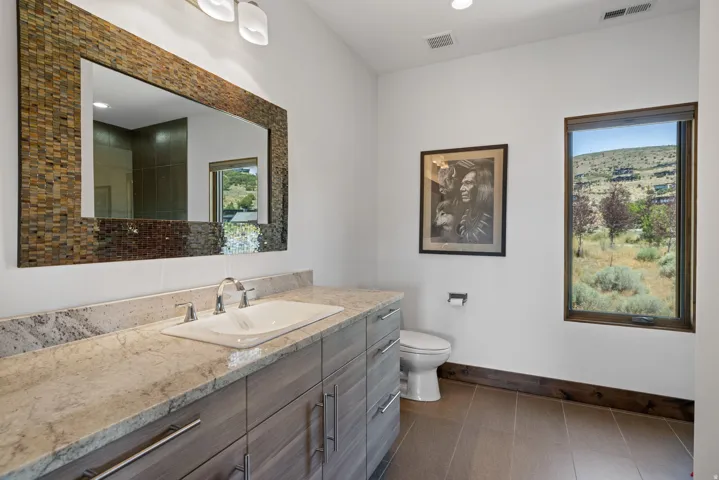 Bathroom vanity with a rectangular undermount sink, dual-handle faucet, and light-toned countertop