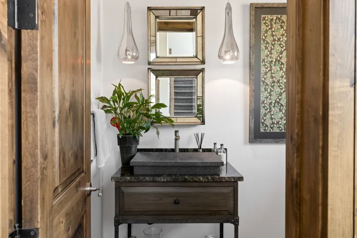 Vanity area featuring a dark stone vessel sink, granite countertop, and a dark wood-finish cabinet with iron accents