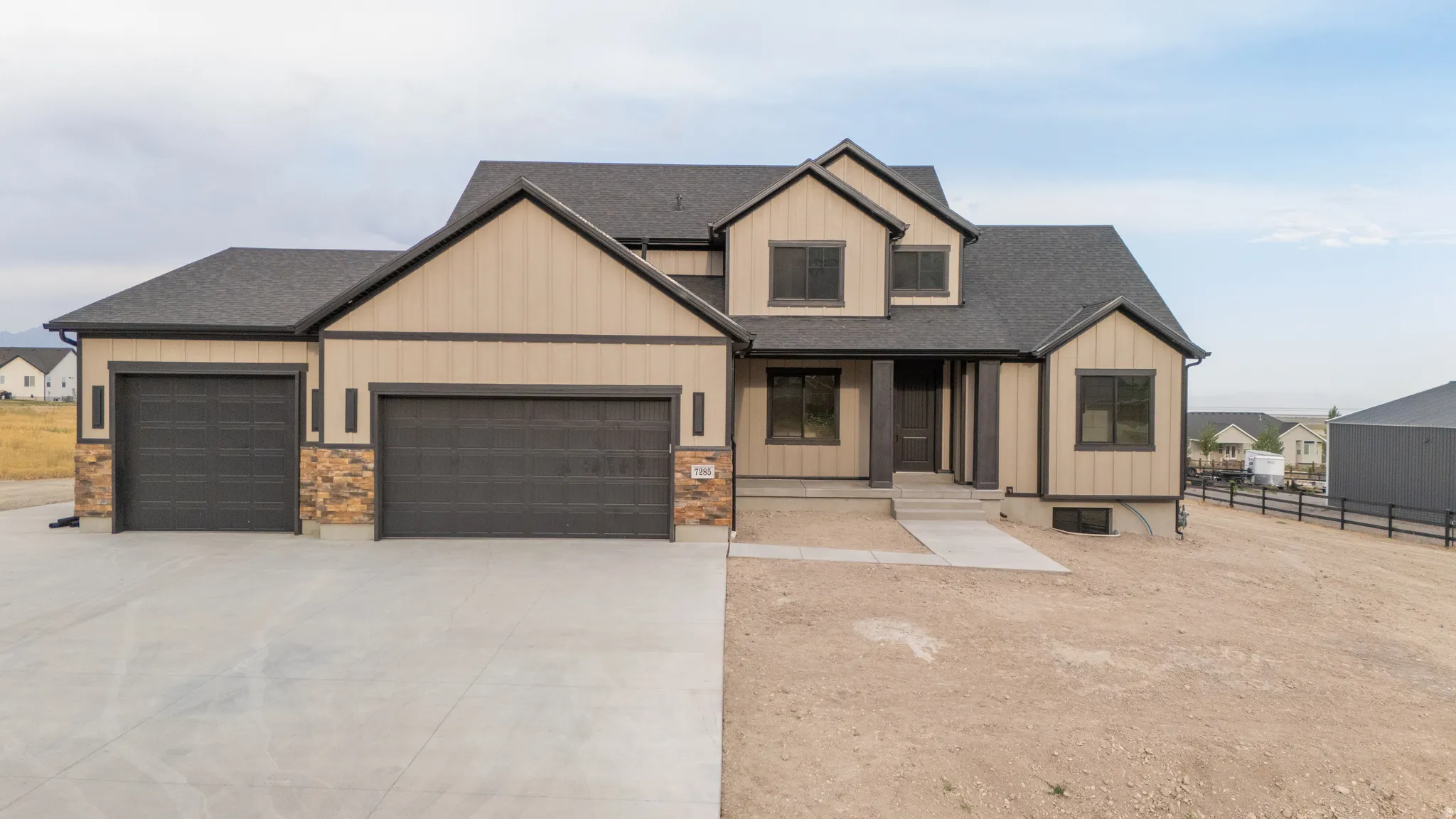 Contemporary two-story residence featuring a neutral-toned exterior with dark trim accents, a multi-gabled roofline, and an integrated three-car garage