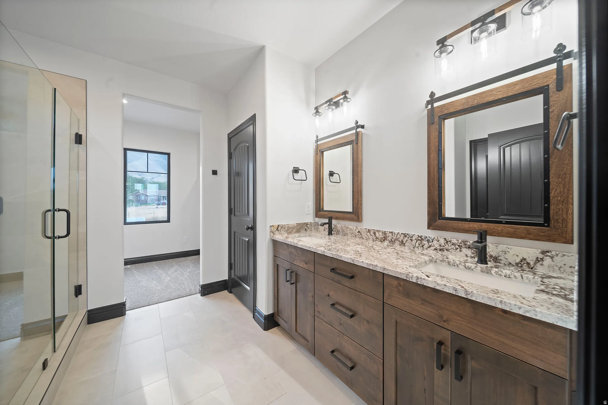 Bathroom featuring a dual vanity with wood-finish cabinetry, stone countertops, and undermount sinks