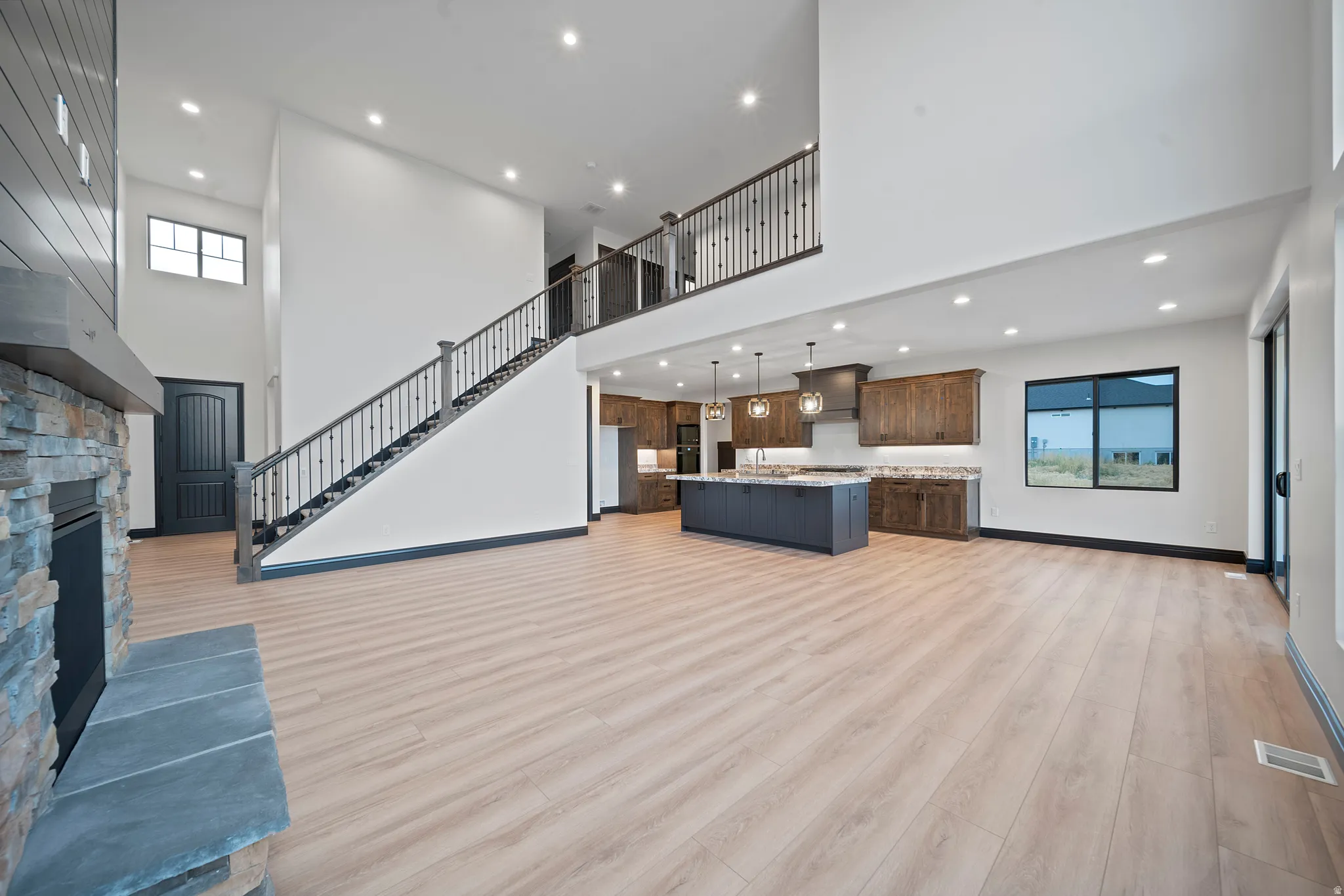 Open-concept living space featuring high ceilings, light wood-finish flooring, and recessed lighting