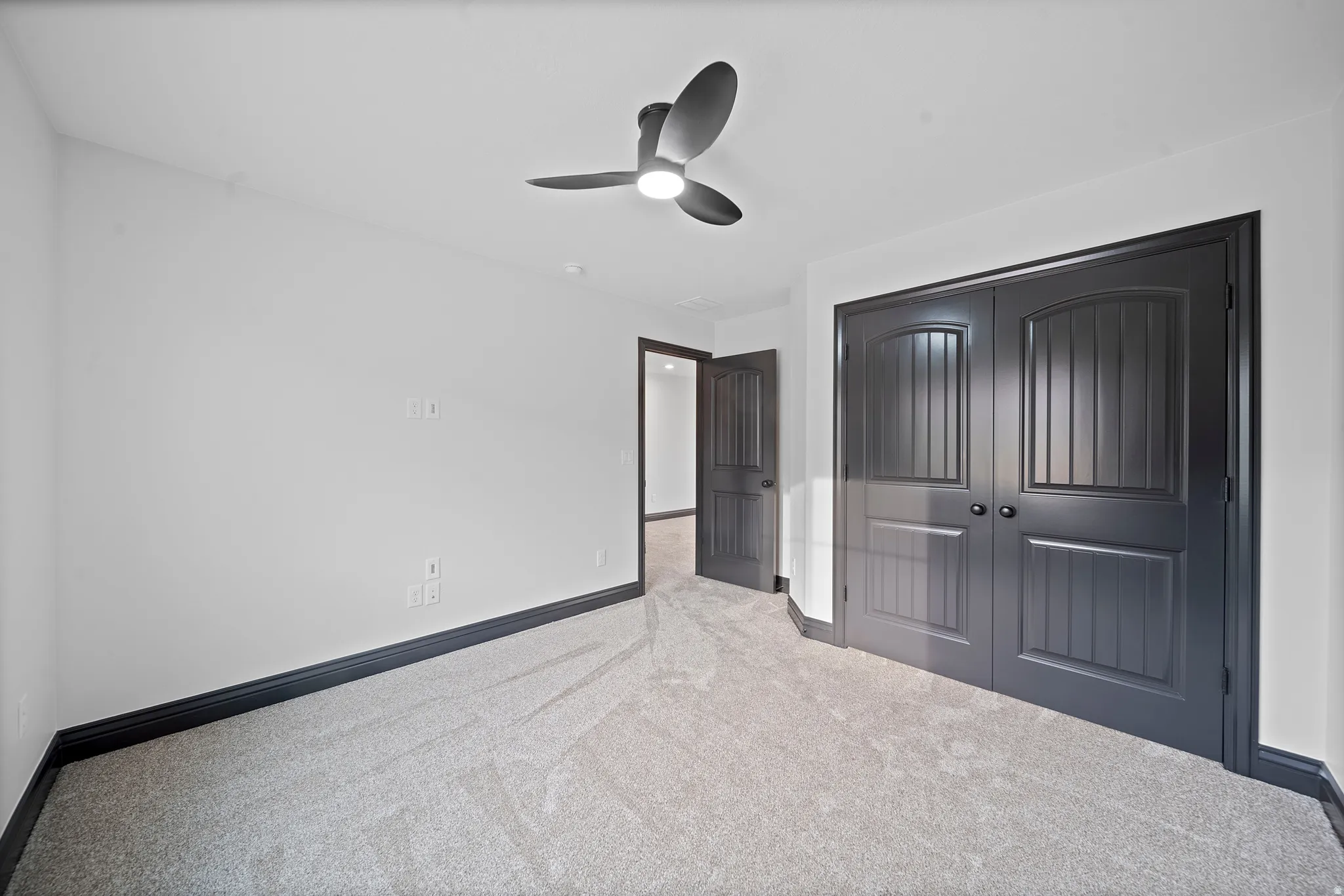Interior room featuring a contemporary ceiling fan with integrated lighting, gray carpeting, and dark trim