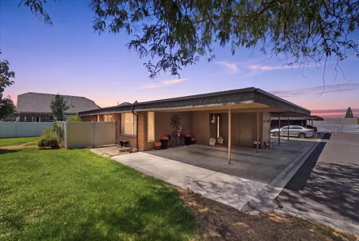 Single-story property featuring a brick facade, covered carport, and a second covered parking area
