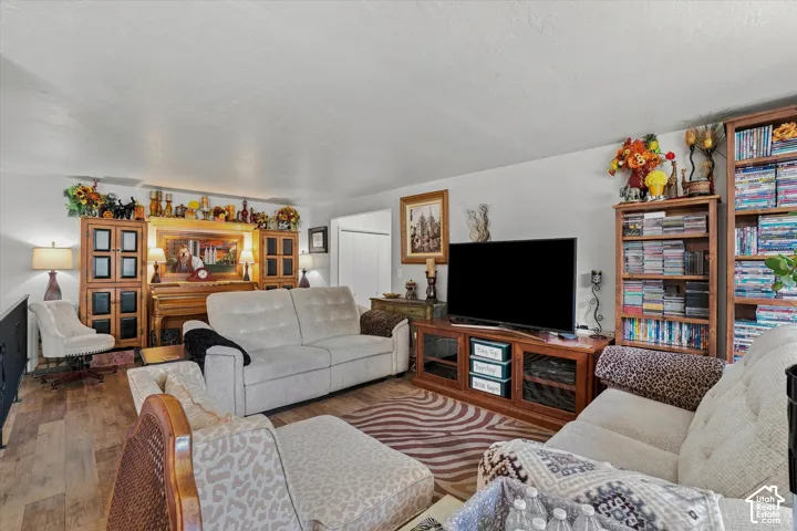 Spacious common area featuring wood-finish flooring, light-toned walls, and a large entertainment console