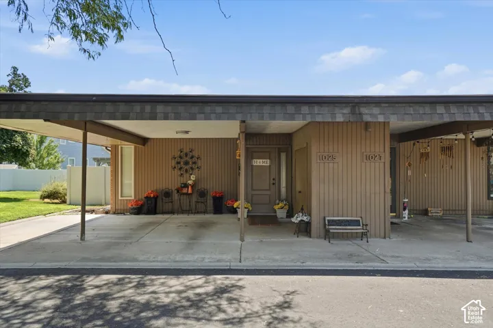 Carport featuring a shingled roof and concrete pad