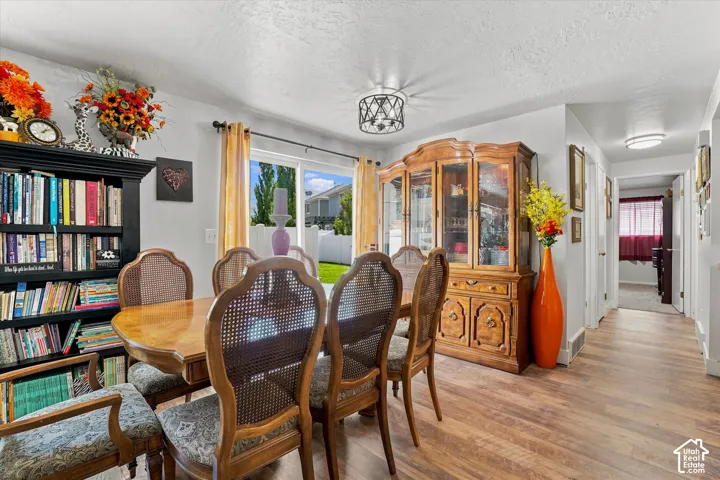 Open-concept dining area featuring wood-finish flooring, a contemporary ceiling light fixture, and sliding glass doors providing access to the backyard