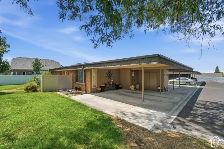 Brick exterior featuring a covered carport, two entry doors, and an attached storage unit