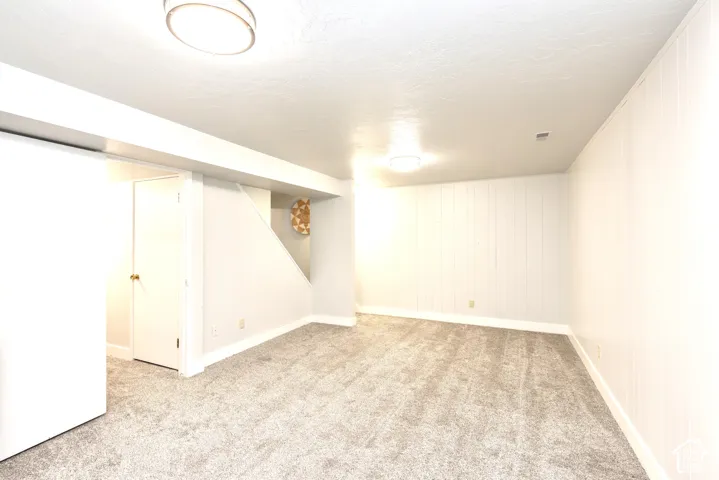 Spacious room with gray textured carpeting, white painted walls, and overhead lighting
