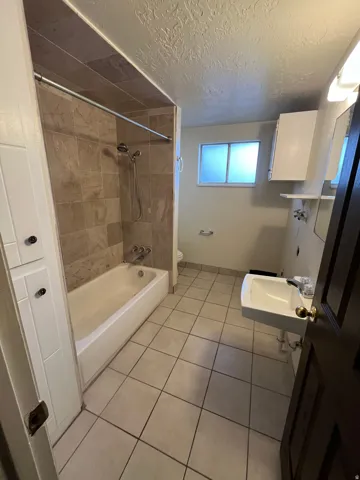 Bathroom featuring floor-to-ceiling tile in the shower, a built-in bathtub, and a wall-mounted sink