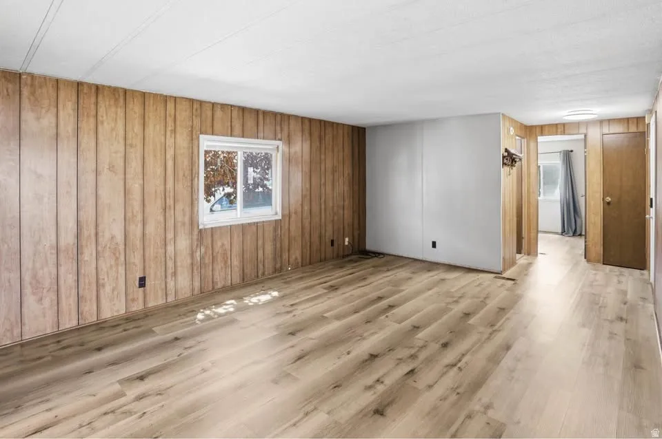 Spacious room featuring wood-finish flooring and vertical wood paneling