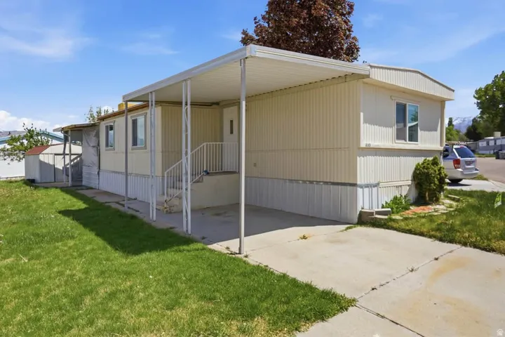 Single-story residence featuring a covered carport, concrete driveway, and a manicured lawn
