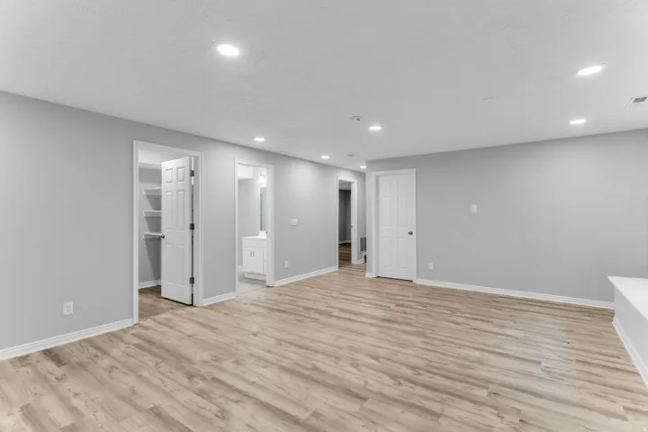 Spacious room featuring wood-finish flooring, recessed lighting, and light gray walls