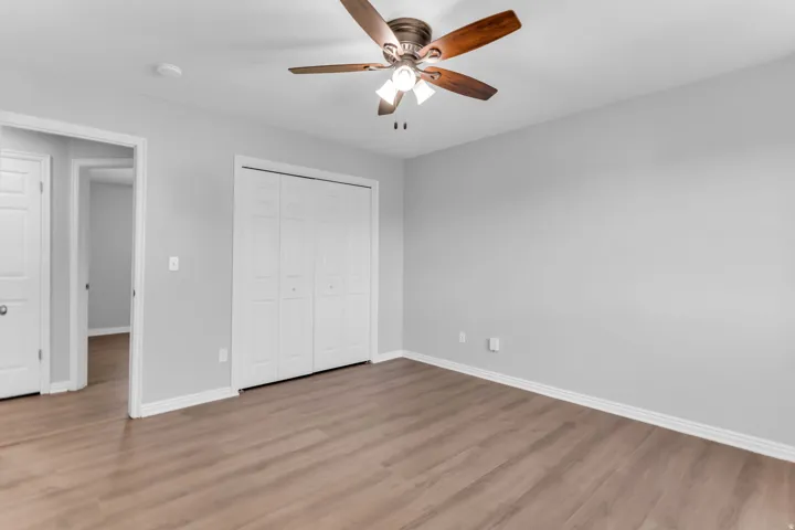 Spacious room featuring wood-finish flooring, light grey walls, and white baseboards