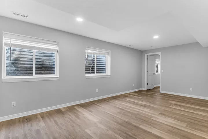 Spacious room featuring light wood-finish flooring, recessed lighting, and crisp white trim