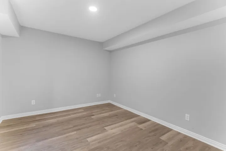 Spacious interior featuring wood-finish flooring, light gray wall paint, white trim, recessed lighting, and ceiling bulkheads