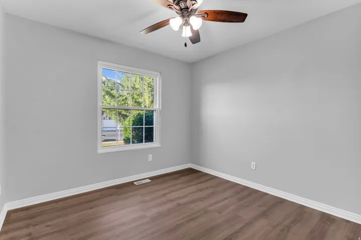 Room featuring gray walls, wood-finish flooring, and white baseboards