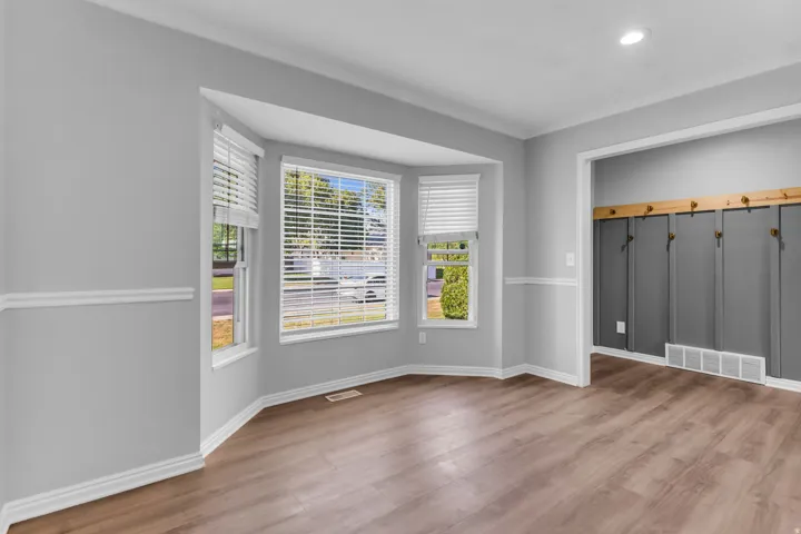 Office w/ bay window & crown molding, wood-finish flooring, and light gray walls with chair rail trim