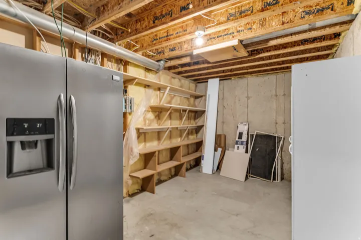 Unfinished basement space featuring exposed wood joists and concrete walls