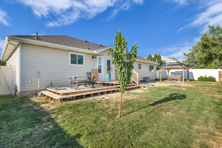 Expansive backyard featuring a tiered wooden deck, a sliding glass door, and a dedicated covered gazebo structure