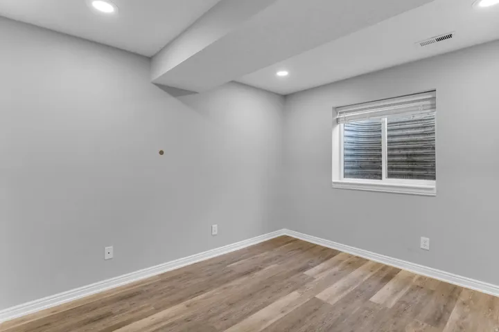 Room featuring light gray walls, wood-finish flooring, white baseboards, and recessed lighting