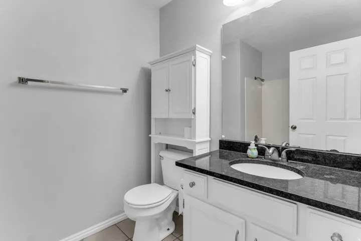Bathroom featuring a white vanity with built-in storage, dark countertop, undermount sink, and chrome fixtures