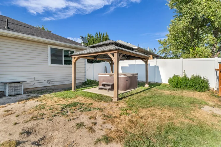 Backyard featuring a hot tub under a wooden gazebo with a metal roof