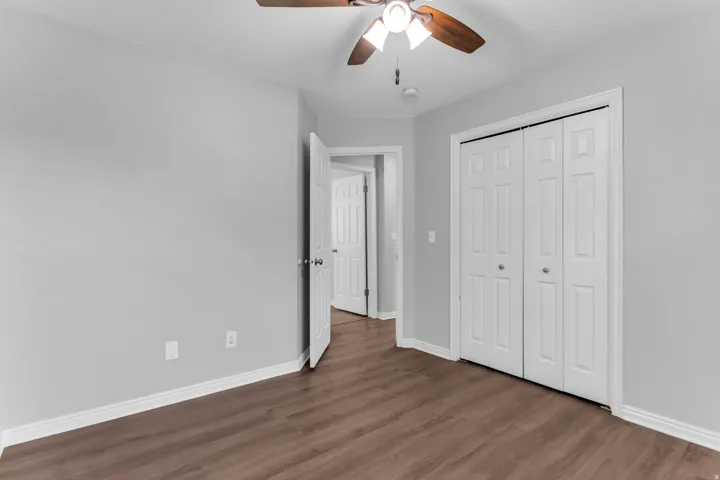 Room featuring wood-finish flooring, light gray walls, white baseboards, and a ceiling fan with integrated lighting