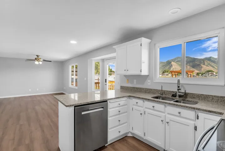 Kitchen featuring white cabinetry, granite countertops, stainless steel appliances, a doubl sink, and wood-finish flooring