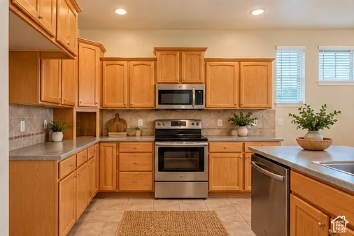 Warm wood cabinetry throughout this kitchen features stainless steel appliances, including a slide-in range and over-the-range microwave, paired with granite countertops