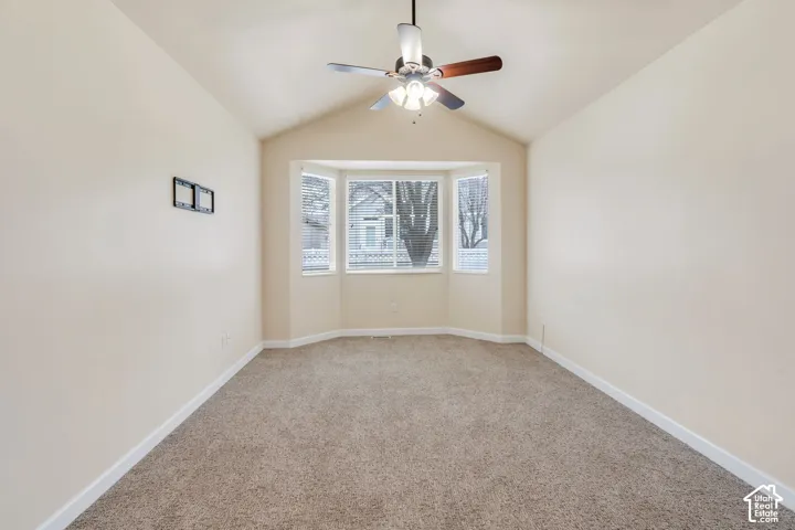 Room featuring a bay window, vaulted ceiling, and ceiling fan with light fixture