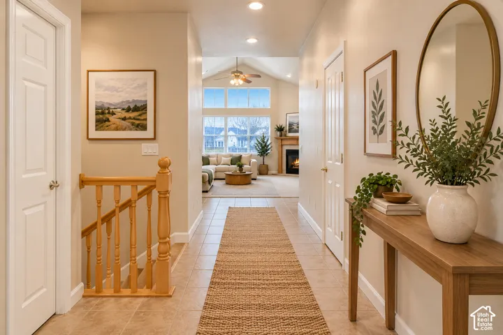 Tile flooring, wood-finish railing, vaulted ceiling with a fan, large windows, and a built-in fireplace