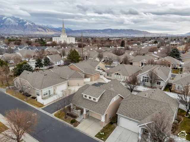 Residential neighborhood featuring single-family homes with gray shingle roofs, an established streetscape, and distant mountain backdrop
