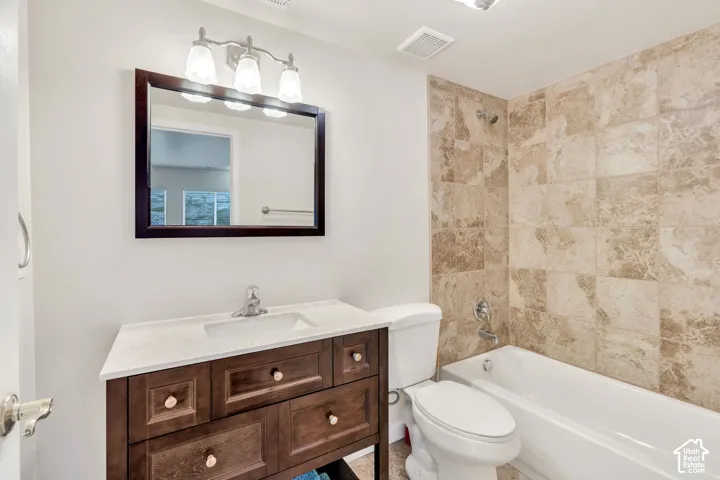 Bathroom featuring a dark wood vanity with a white countertop, an undermount sink, a framed mirror, and a three-light fixture