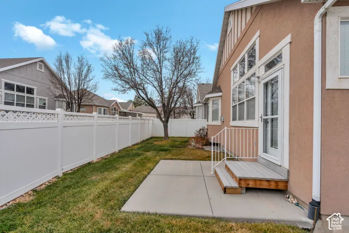 Private outdoor space featuring a concrete patio, wood steps with metal railing, and a fully fenced yard