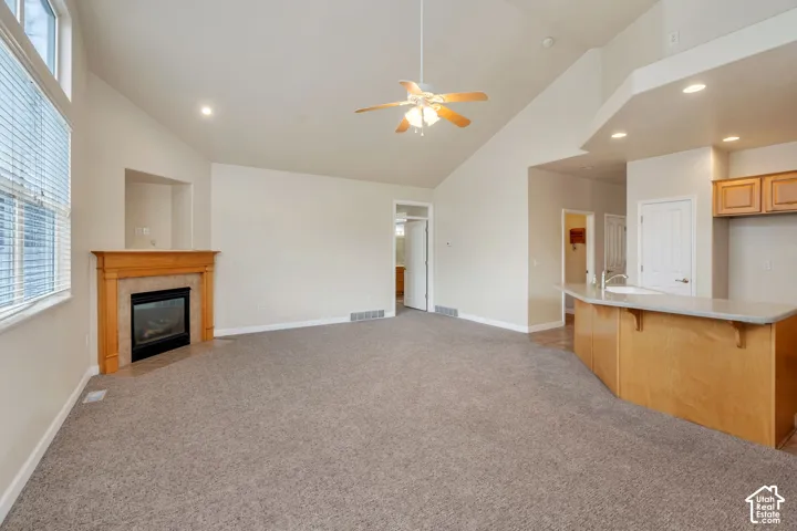 Spacious living area featuring vaulted ceilings, a fireplace with a wood mantel, and large windows