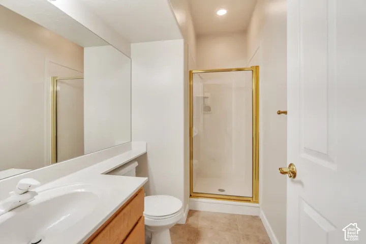 Bathroom featuring a wood-finish vanity with an integrated sink and countertop, a frameless mirror, a shower with a gold-finish frame, and recessed lighting