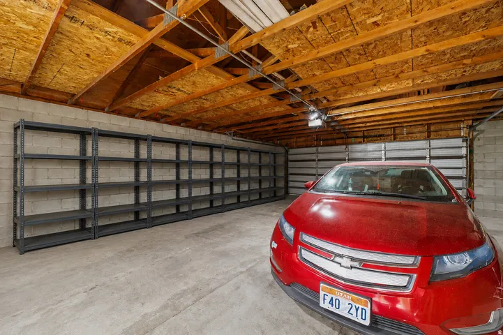 Spacious garage featuring a concrete floor, concrete block walls, exposed wood beam ceiling, and multiple garage doors
