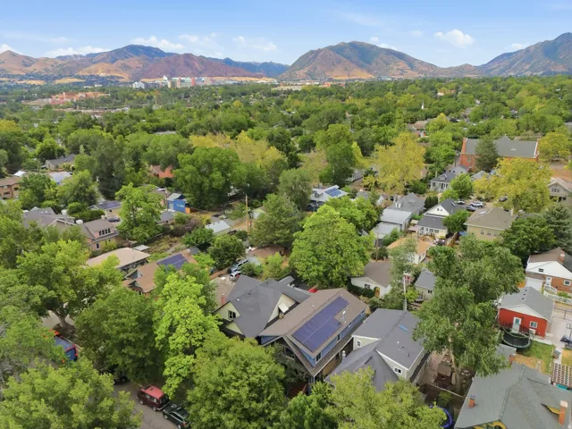 Aerial perspective showcasing a residential area with mature trees and mountain backdrops
