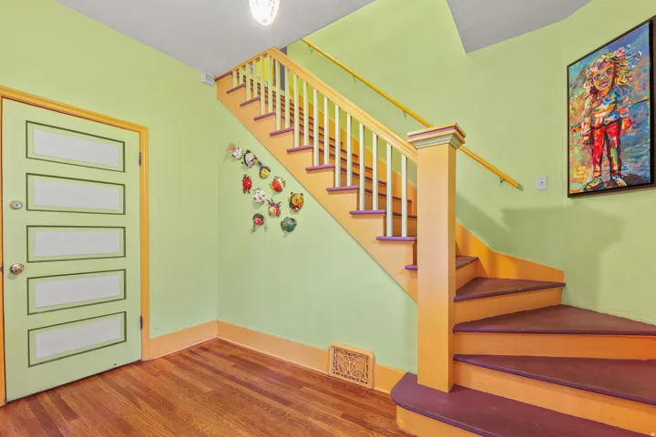 Hardwood flooring complementing a brightly painted staircase with white balusters