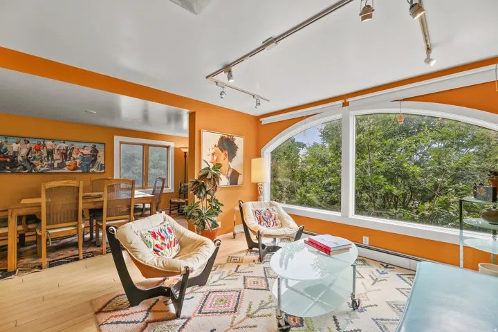 Living area featuring a large arched window, track lighting, and wood-finish flooring
